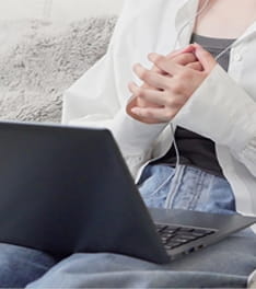 ノートパソコンを膝に乗せて座っている人の写真