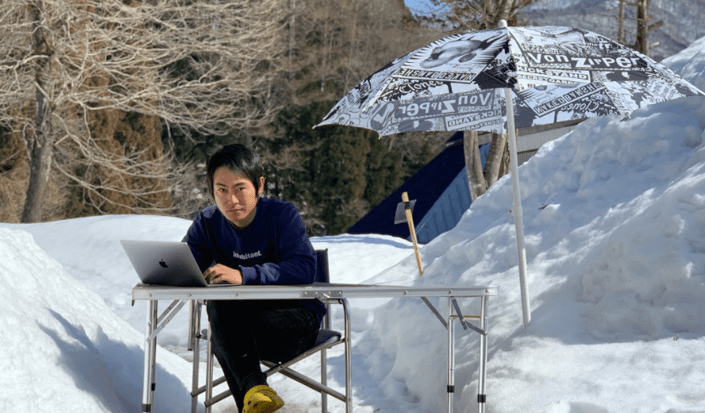 雪が積もった庭にテーブルを出して仕事している飯田さん