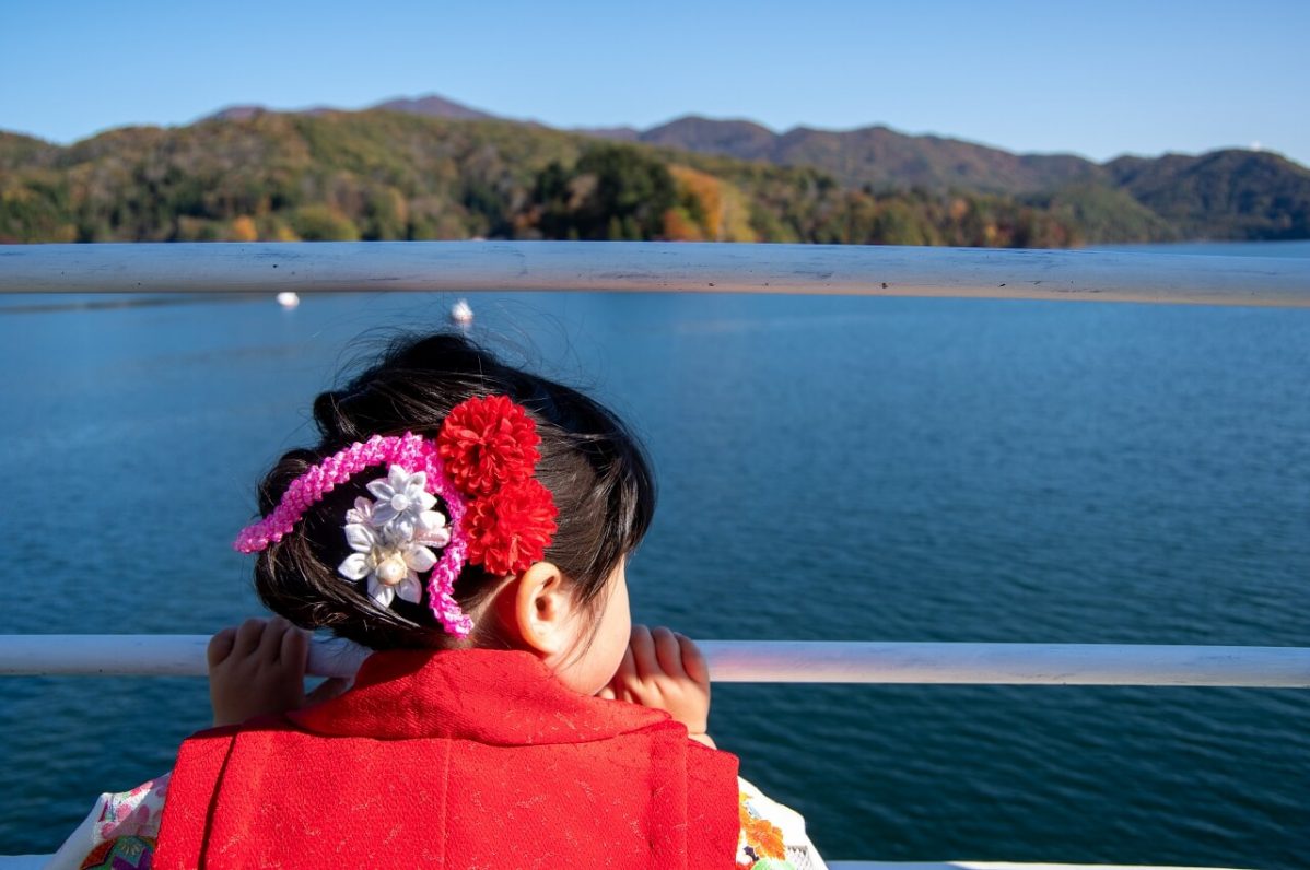 長野県信濃町野尻湖の宇賀神社へ向かう遊覧船から、少女が湖を見ているところ